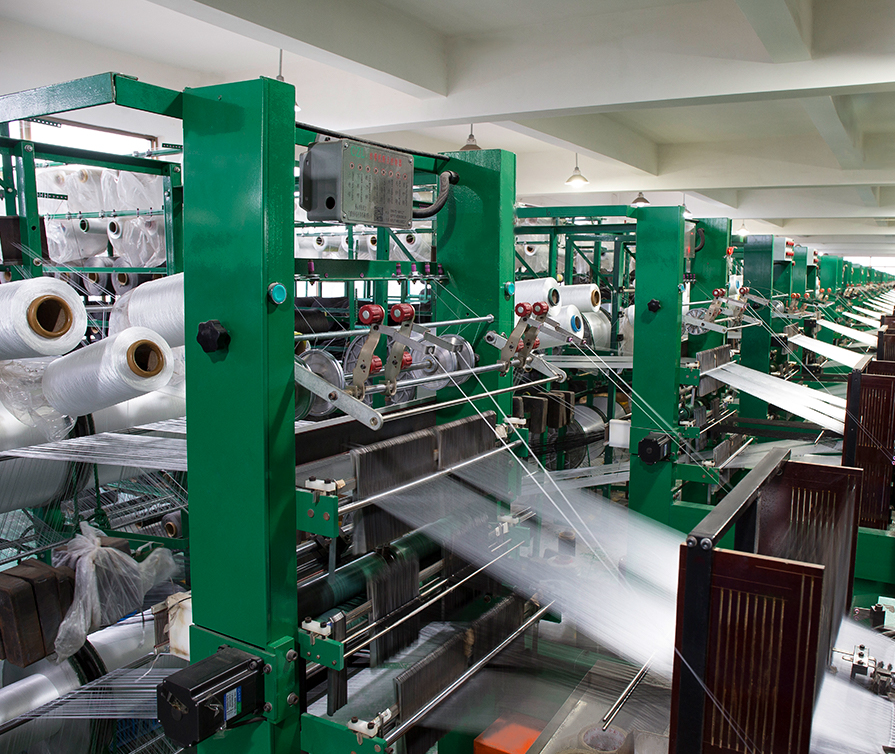 Rows of yarn spools feeding weatherstrip production equipment