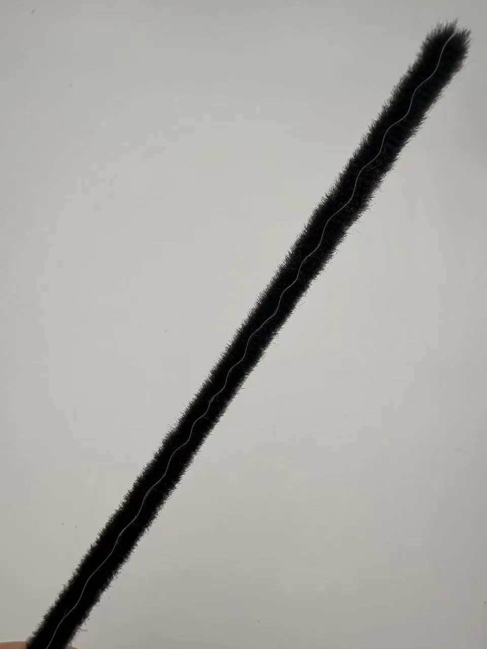 Black regular non-siliconed wool pile weatherstrip length on a white background